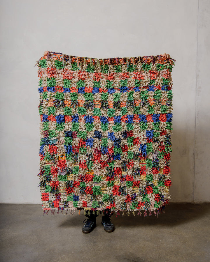 Multicoloured textured rug against a plain wall.