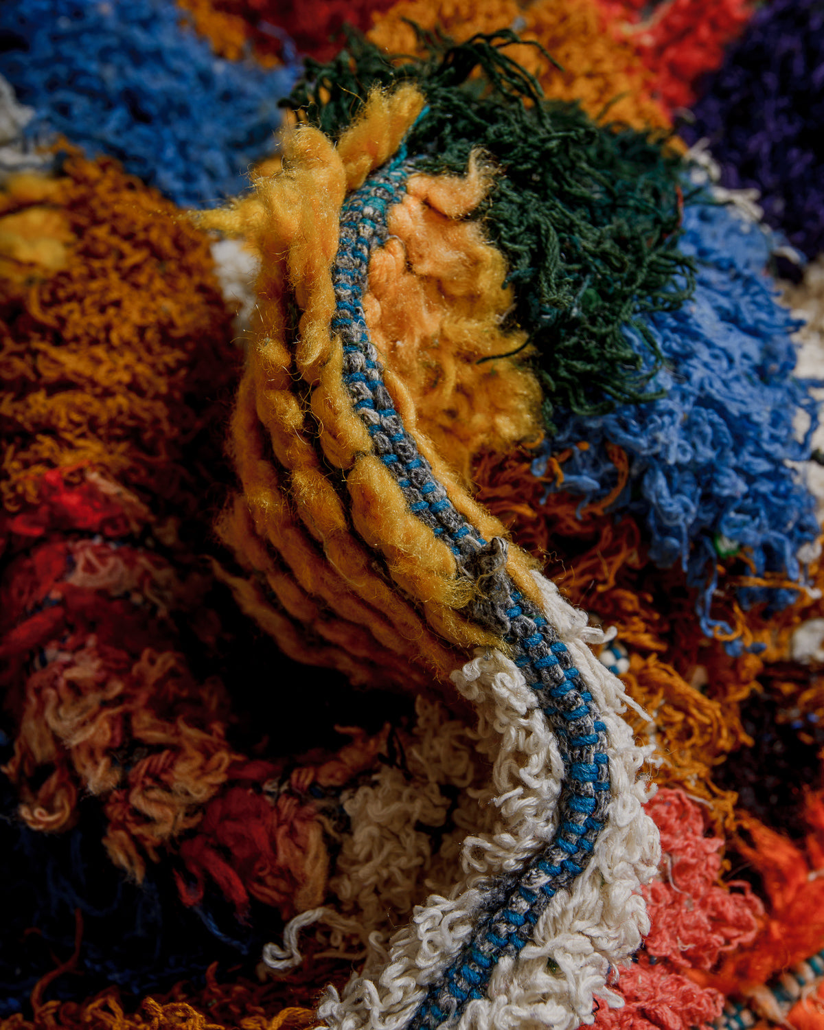 Close-up of a colorful textured rug with a blue thread running through it.