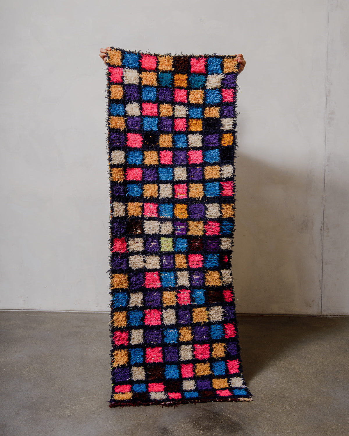 Multicoloured square-patterned rug on a plain background