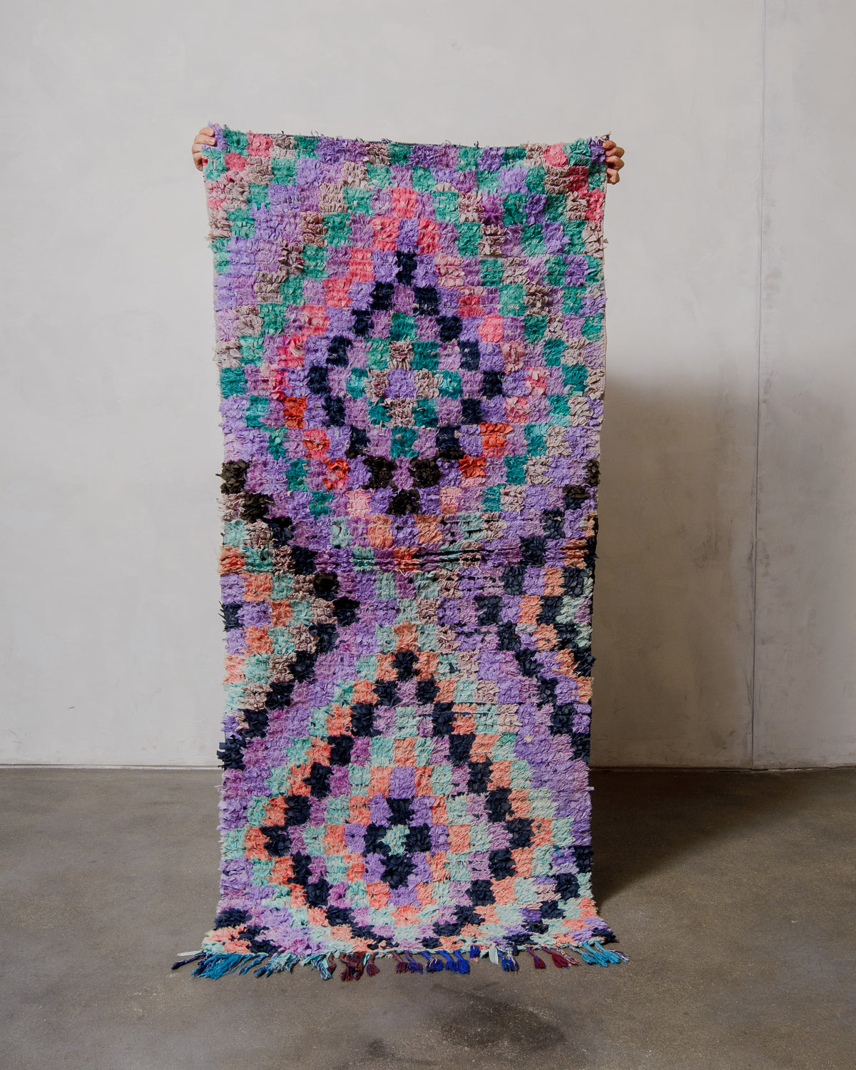 Colourful geometric-patterned rug on a plain background.
