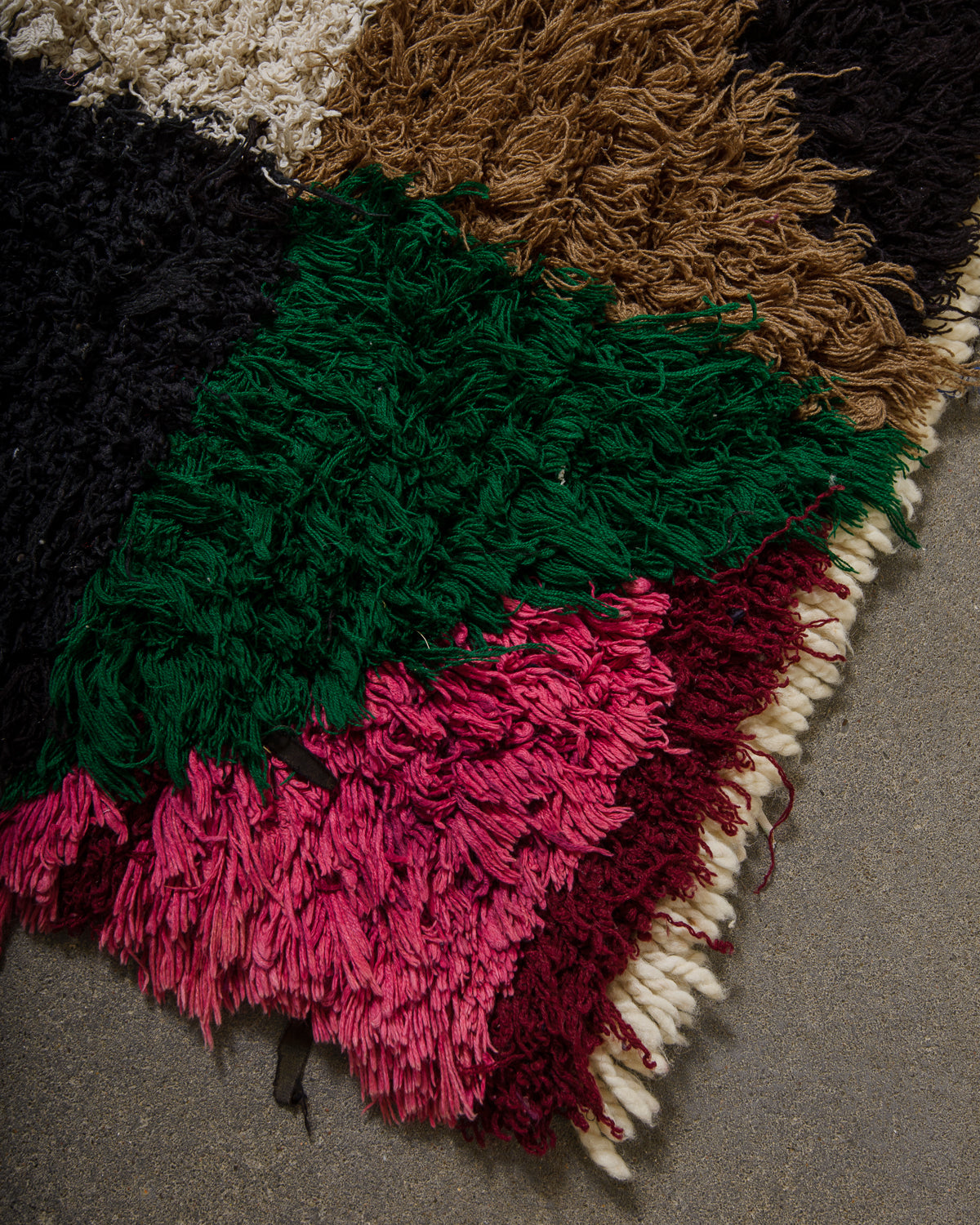 Multicolored textured rug with a geometric pattern on a gray floor.