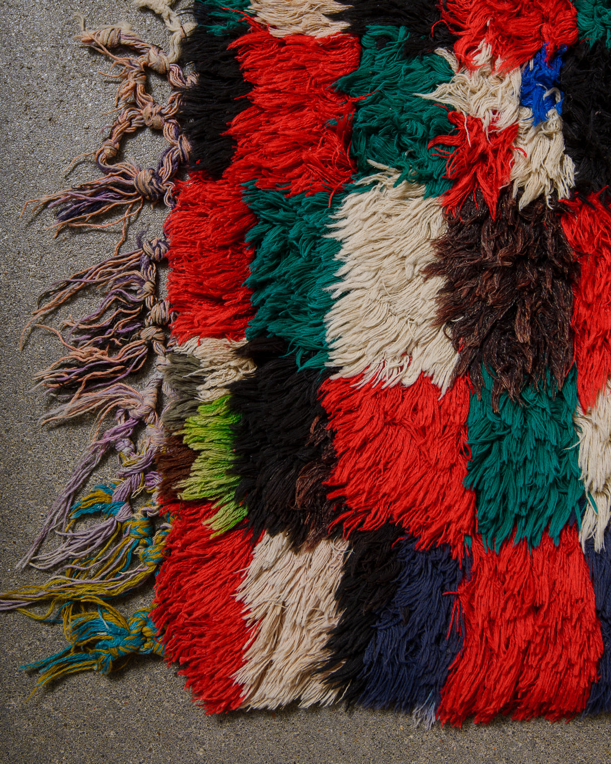Multicolored textured rug with tassels on a gray surface