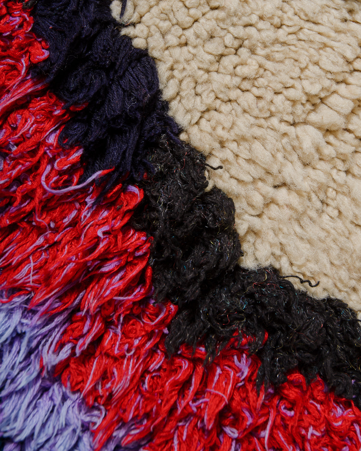 Close-up of a textured rug with red, black, and beige colors.