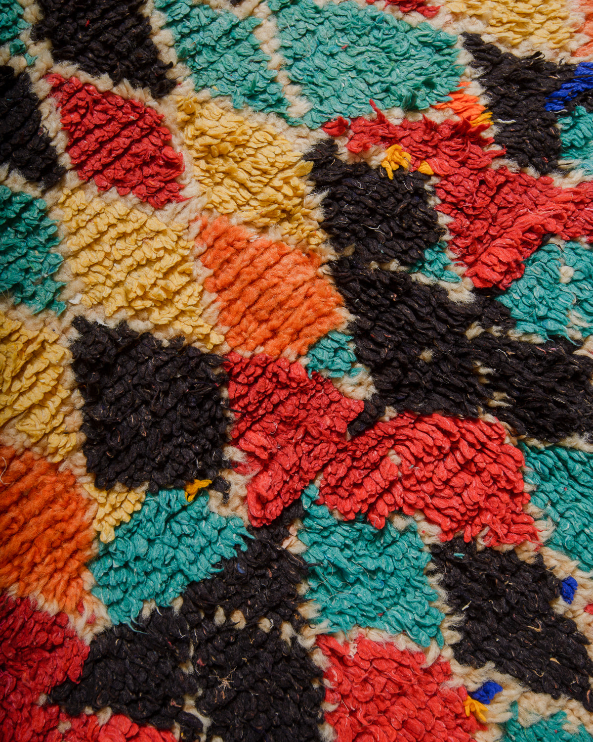Close-up of a colorful geometric-patterned rug with red, black, yellow, and blue colors.