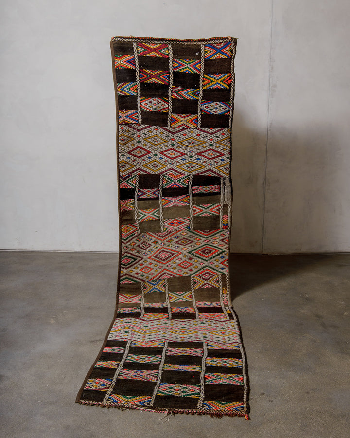 Colourful patterned kelim rug on a plain background.
