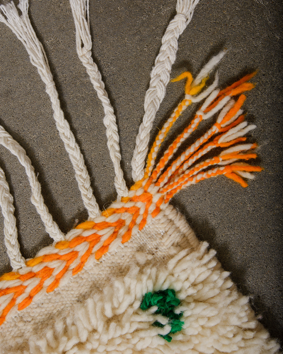 Corner of Azilal rug with white cotton tassels and bright, yellow and orange weaving across the edge.