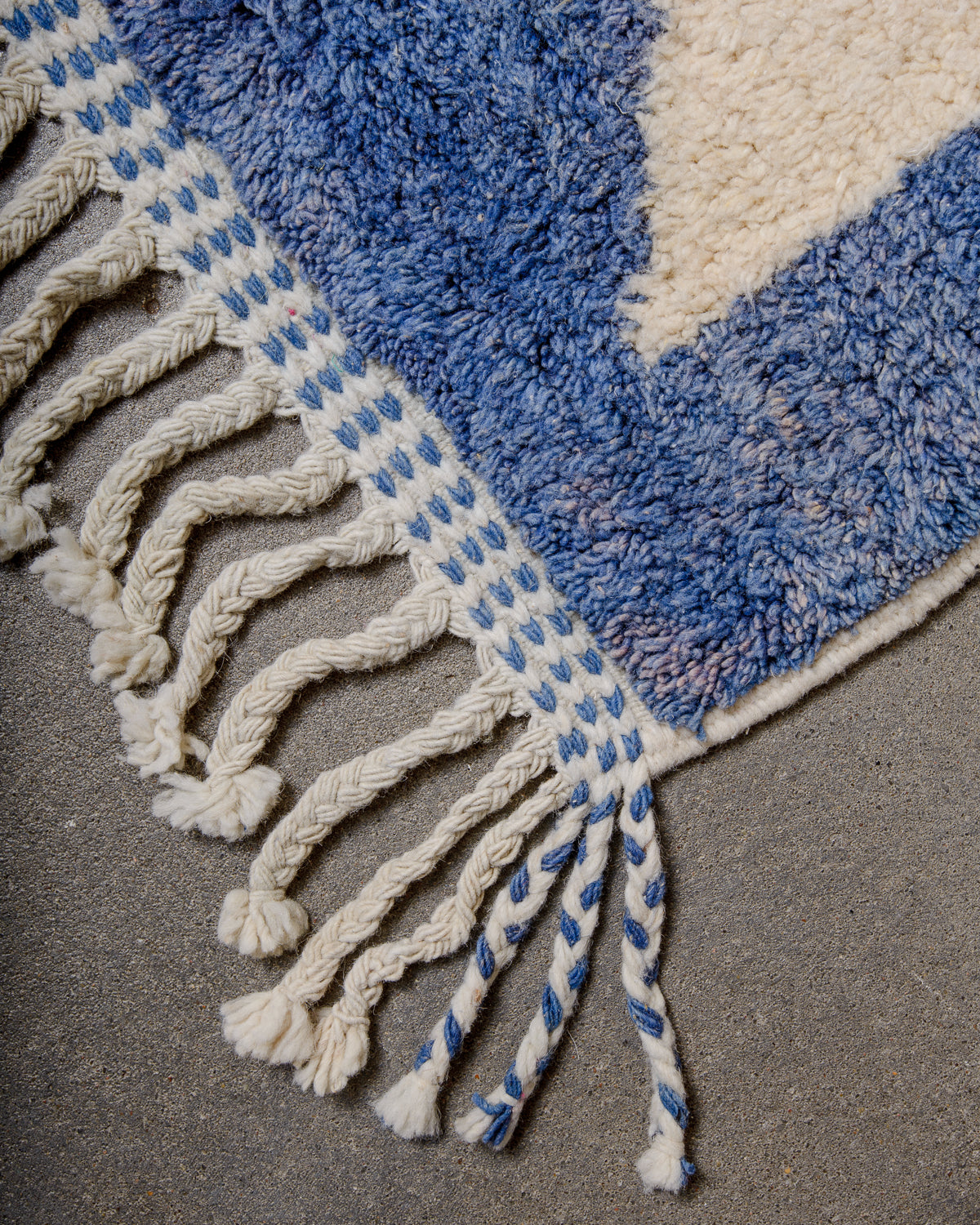 Tasseled end of blue and cream wool runner rug. 