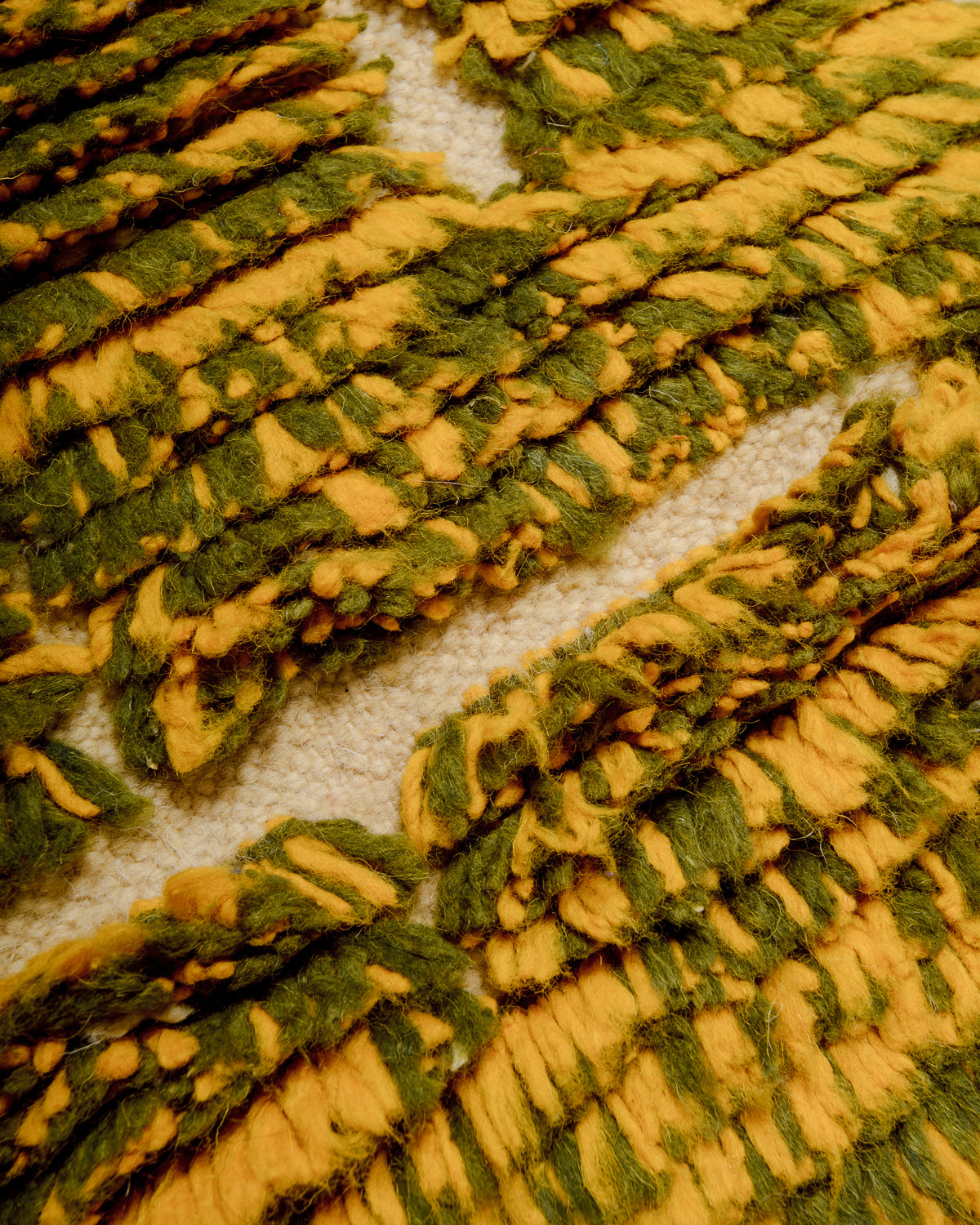 Texture of rug made of knotted yellow and olive wool and flat woven cream wool. 