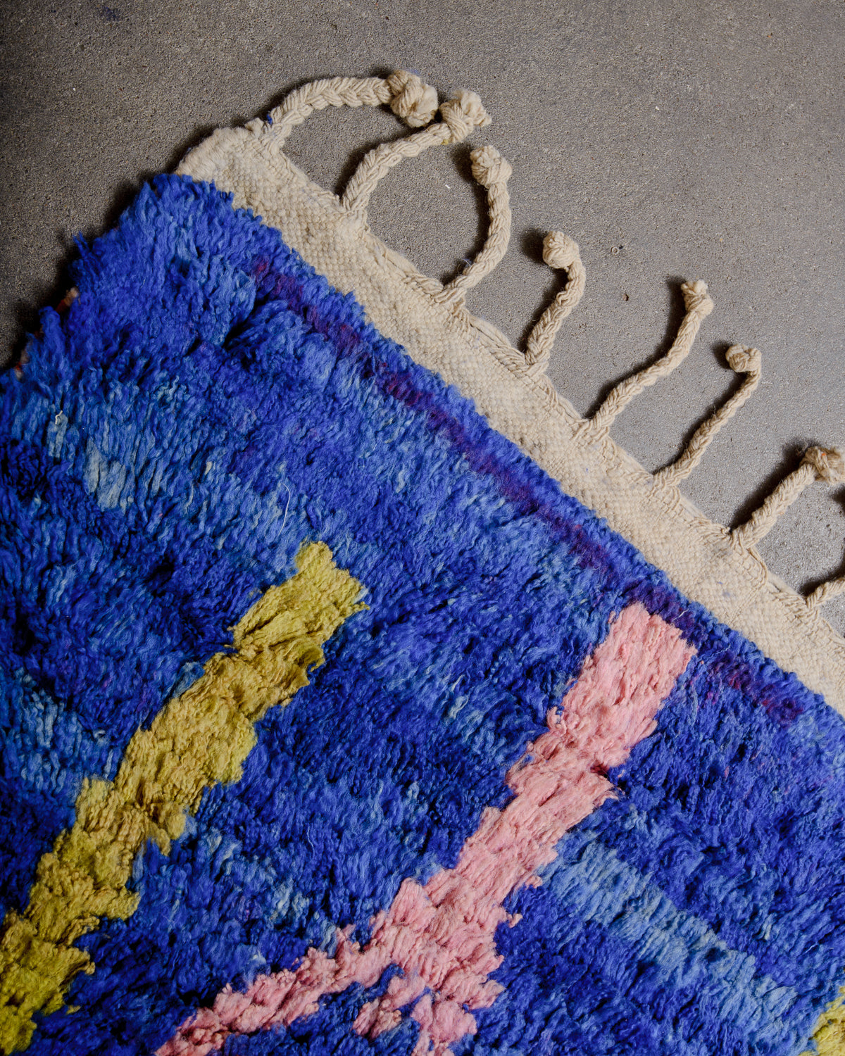 Corner of vintage rug with colourful wool and natural wool tassels. 