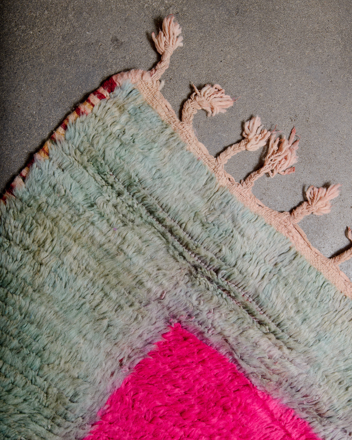 Corner of vintage rug with colourful wool and natural wool tassels. 