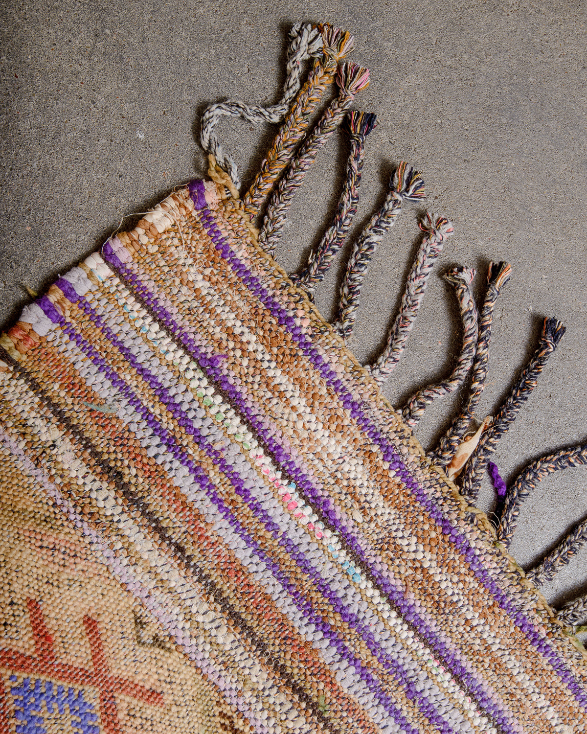Corner of vintage Kelim rug with multicoloured cotton tassels. 