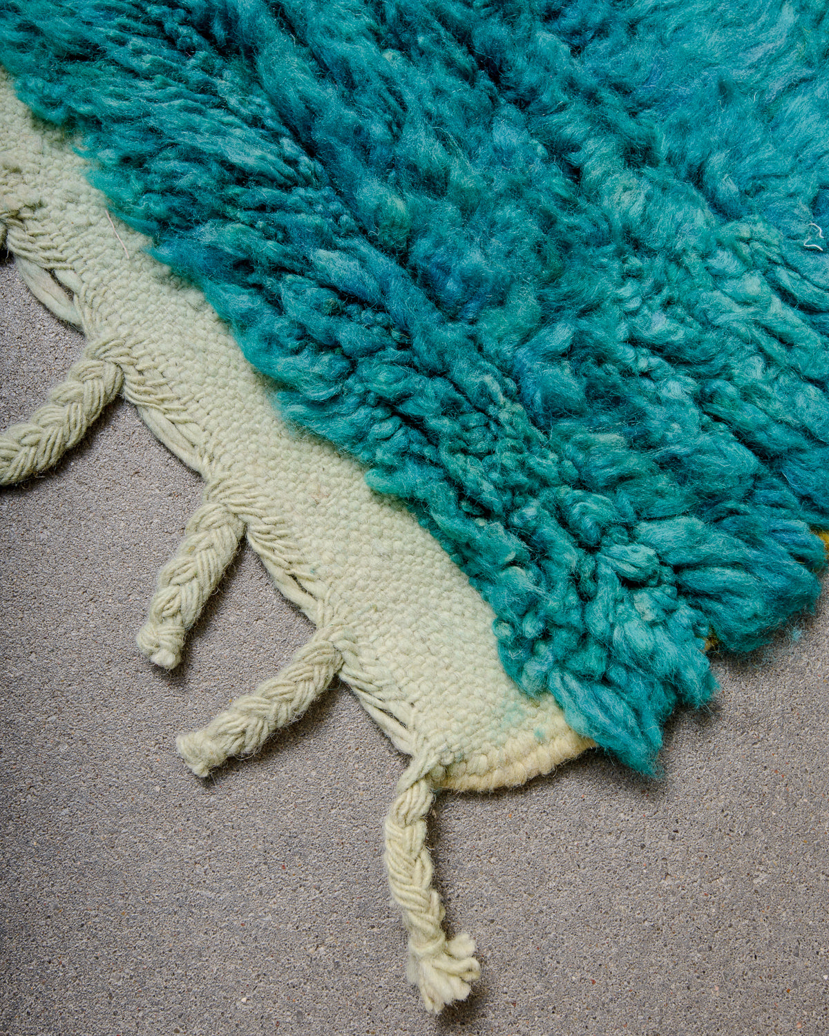 Corner of Berber runner rug with colourful wool pile and natural wool tassels. 