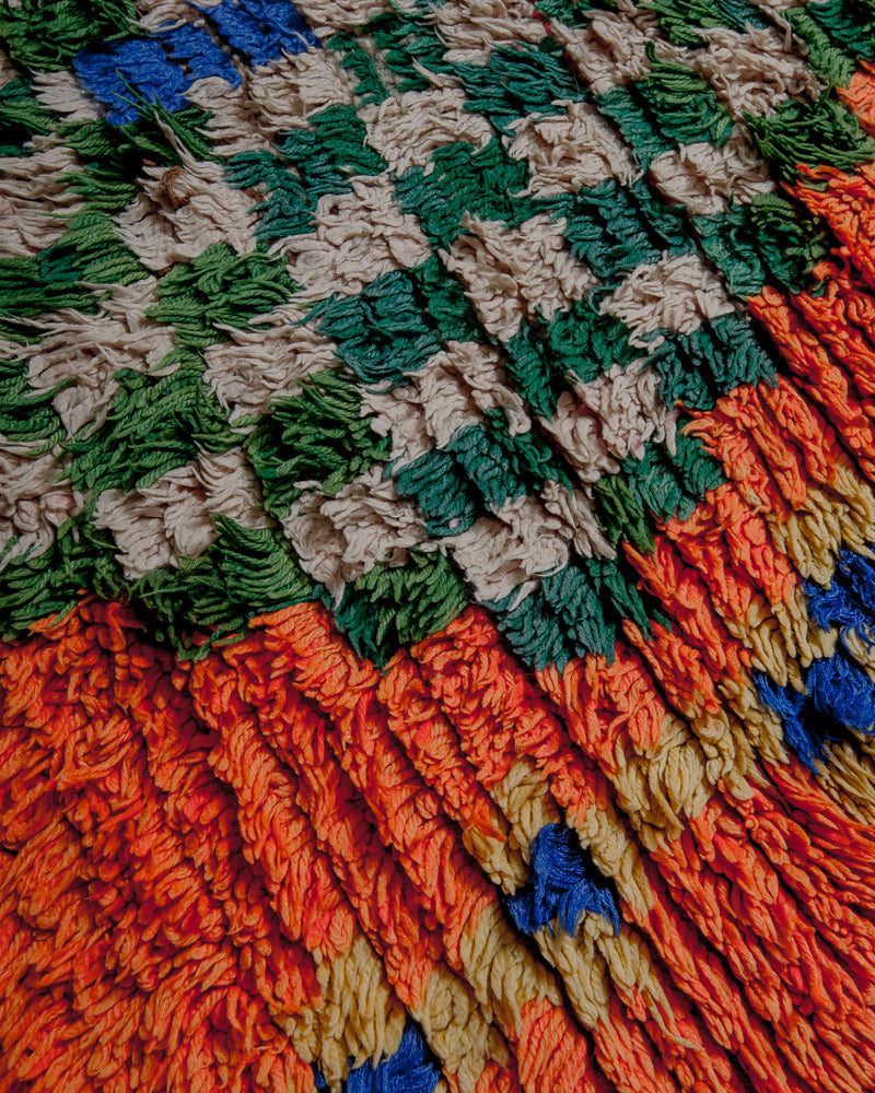 Surface of boucherouite rug with orange, yellow, blue, green and white yarn.