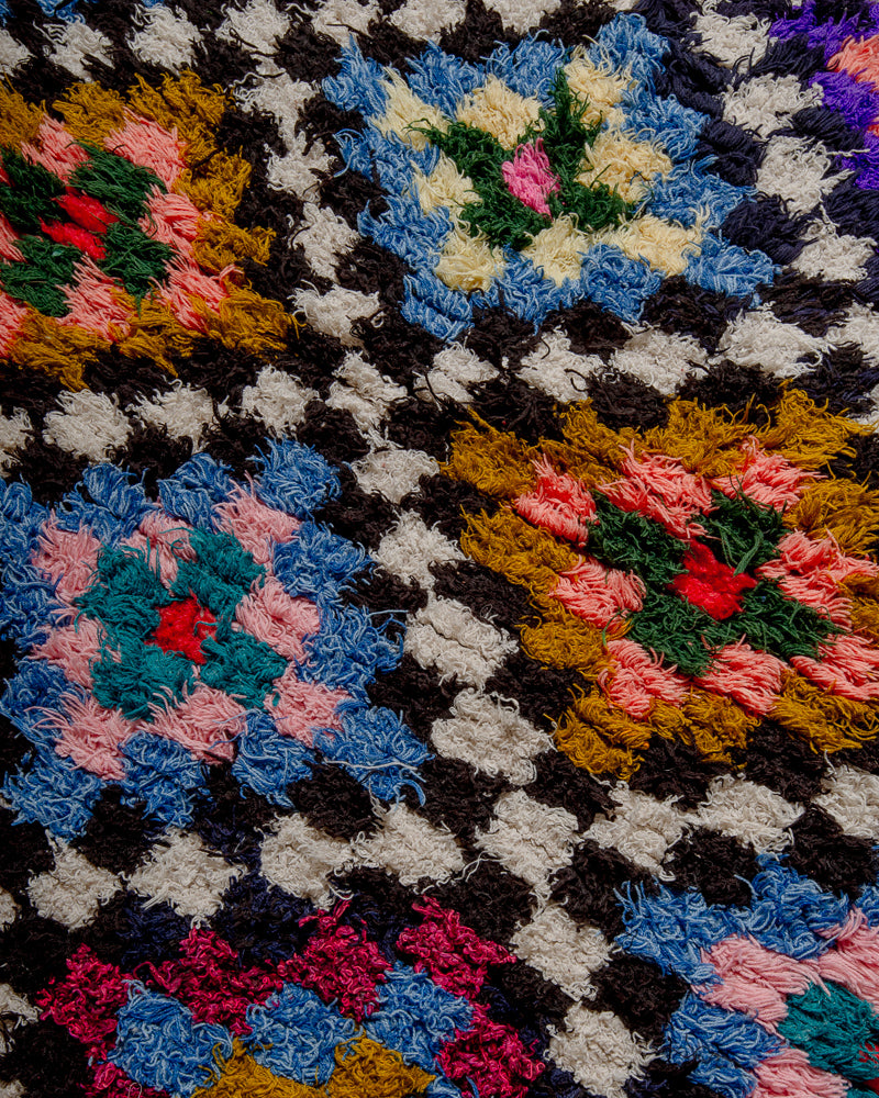 close up of surface of boucherouite rug with many coloured squares.