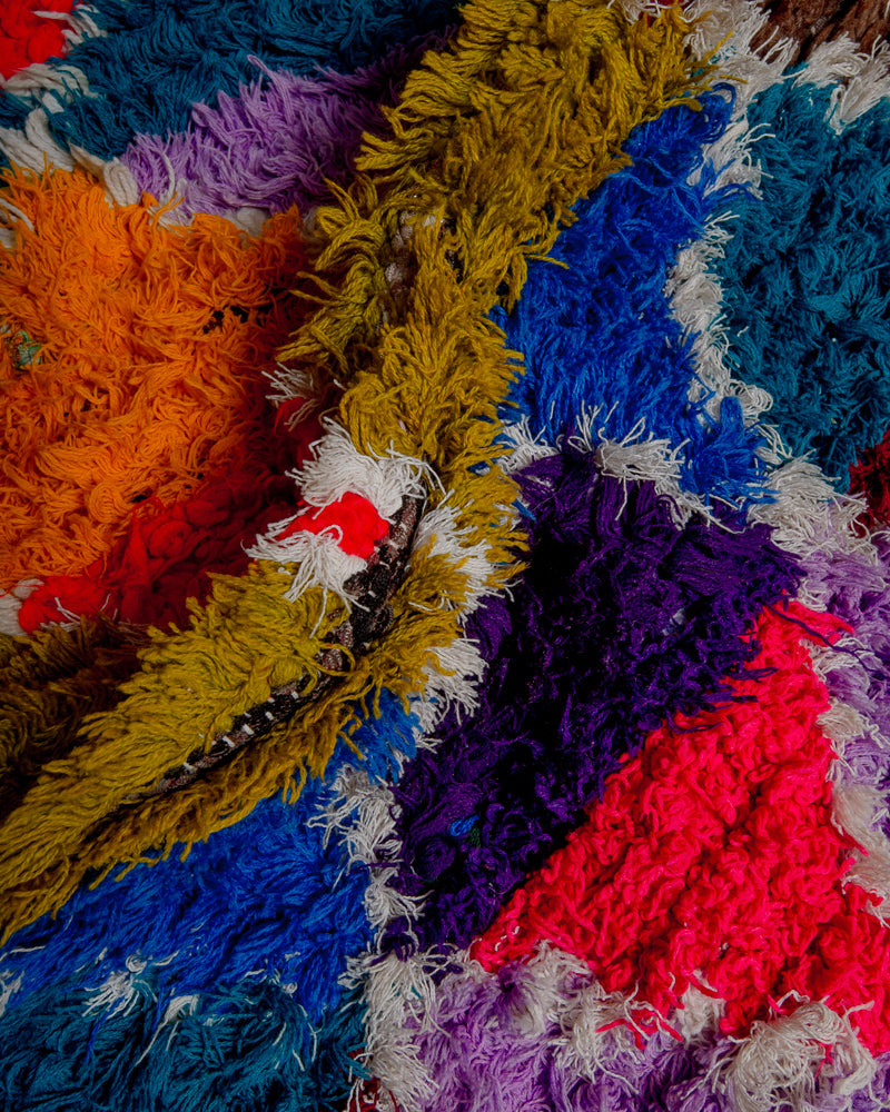Close up of boucherouite rug with red, mustard, orange, blue and purple cotton.