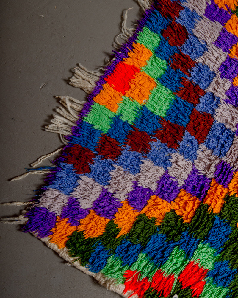 Corner of vintage rug with sparse or missing tassels.