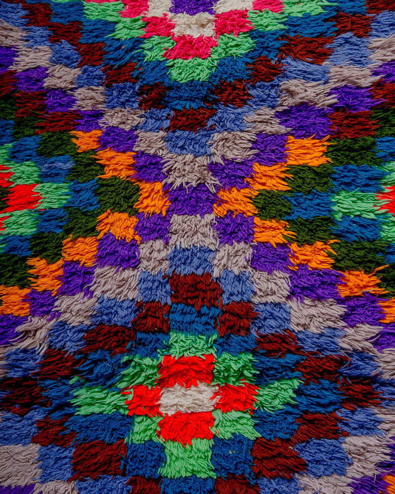 close up of surface of boucherouite rug with many coloured squares.