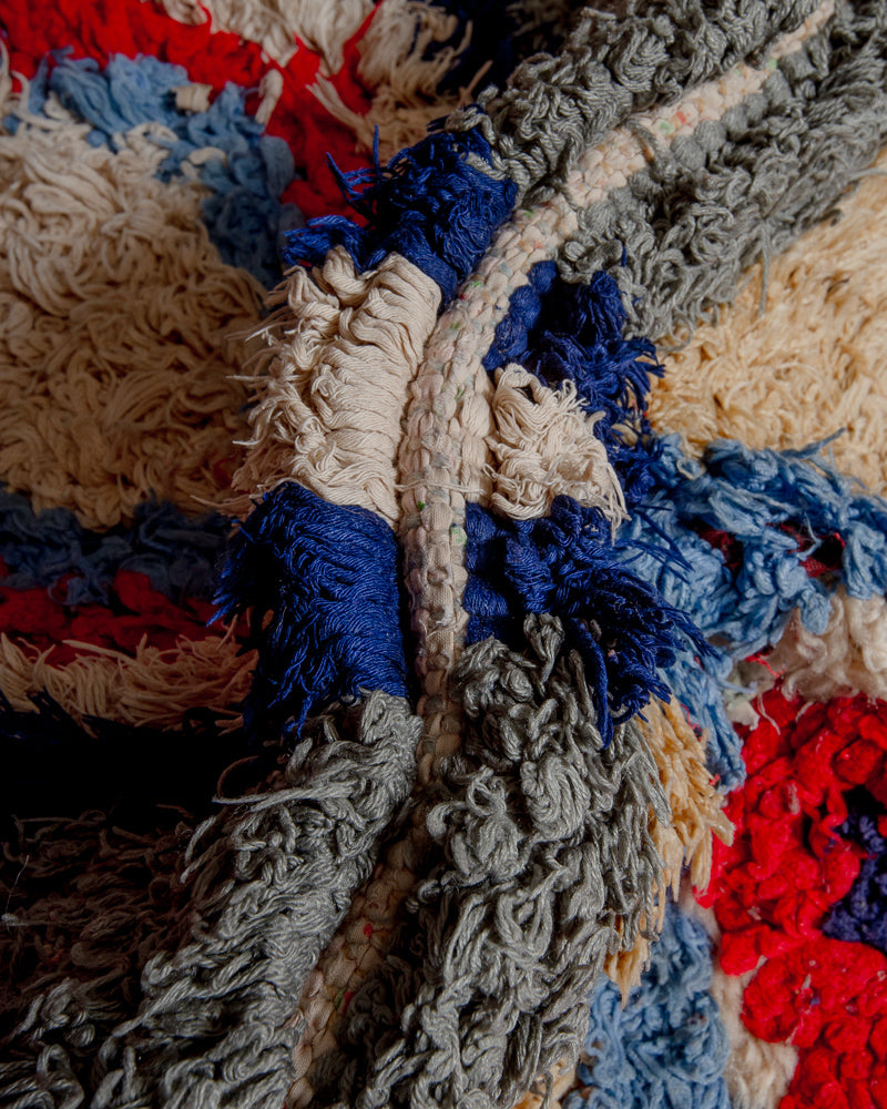 Close up of boucherouite rug with blue, red, grey and white yarn.